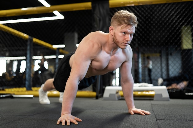 Full shot shirtless man training at gym