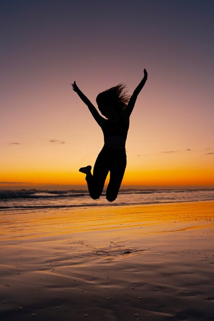 Full shot  silhouette jumping at sunset