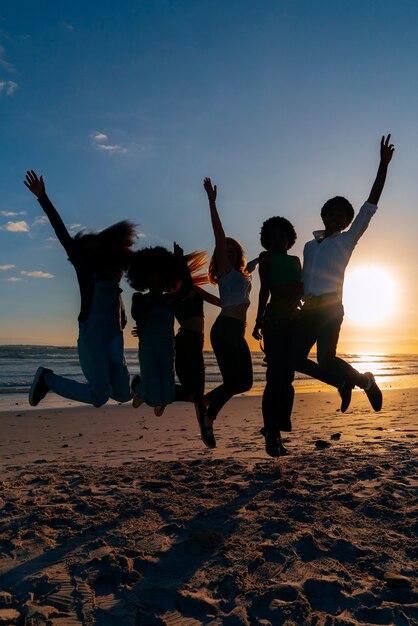 Full shot  silhouettes of people jumping at sunset