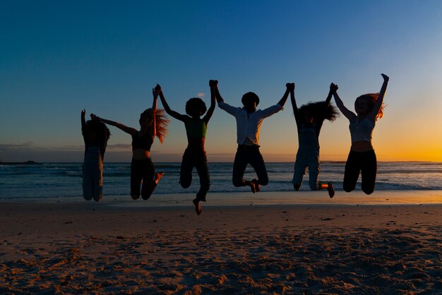 Full shot  silhouettes of people jumping at sunset