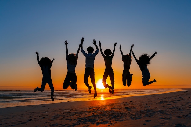 Free Photo full shot  silhouettes of people jumping at sunset