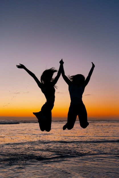 Free photo full shot  silhouettes of people jumping at sunset