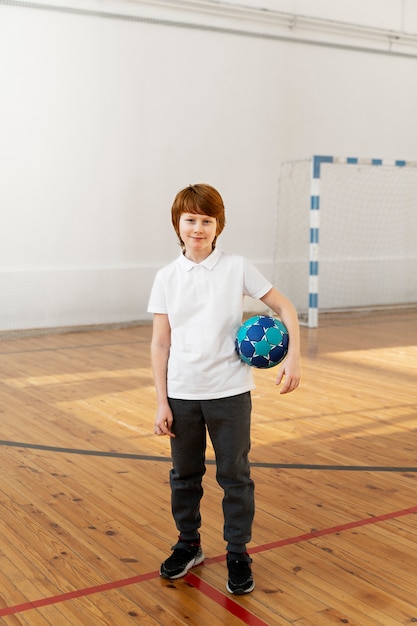 Free photo full shot smiley boy holding ball