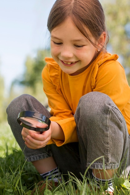 Full shot smiley girl holding magnigying glass