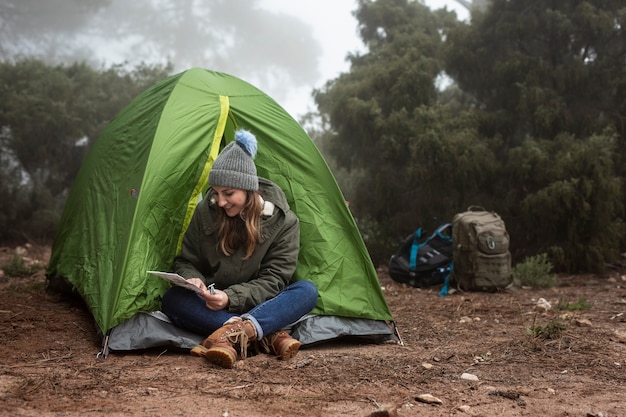 Full shot smiley girl sitting near tent