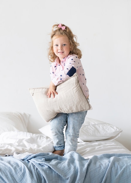 Free Photo full shot smiley girl with pillow in bed