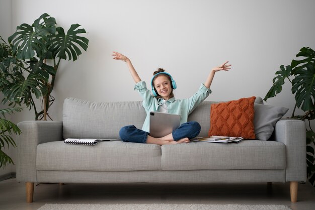 Full shot smiley girl with tablet and headphones