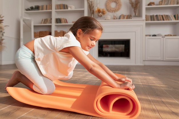 Full shot smiley girl with yoga mat