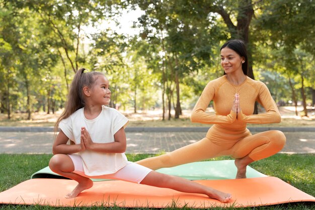 Full shot smiley girl and woman doing yoga