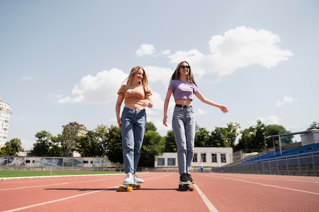 Full shot smiley girls with penny boards outdoors