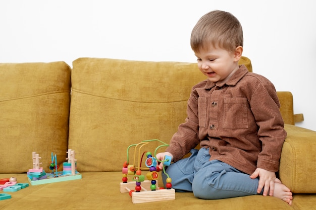 Full shot smiley kid on couch playing