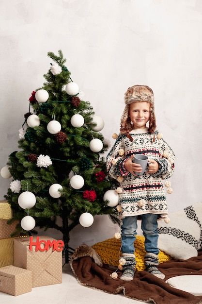 Free photo full shot smiley kid near the christmas tree