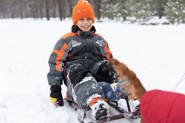 Full shot smiley kid sitting on sleigh