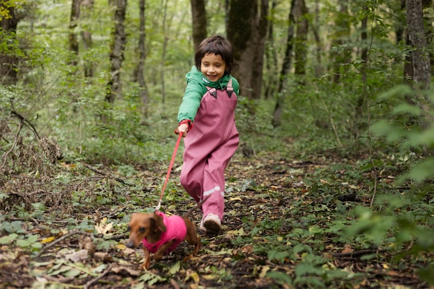 Full shot smiley kid walking dog in nature