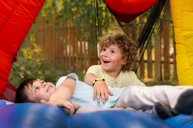 Full shot smiley kids playing in bounce house