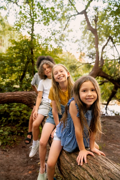 Full shot smiley kids sitting on log