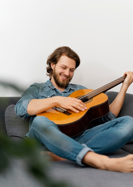 Full shot smiley man playing guitar