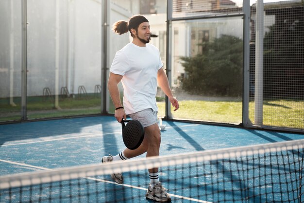 Full shot smiley man playing paddle tennis