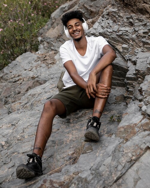 Full shot smiley man sitting on rock