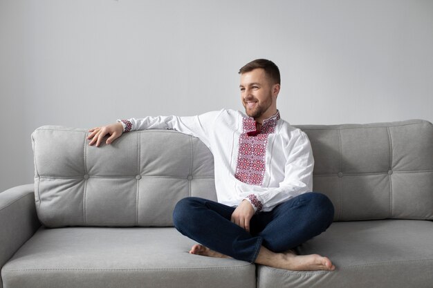 Full shot smiley man with ukranian shirt on couch