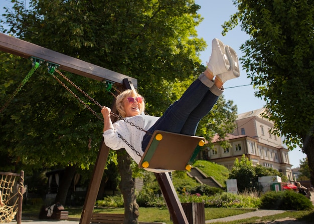 Free photo full shot smiley senior woman on swing