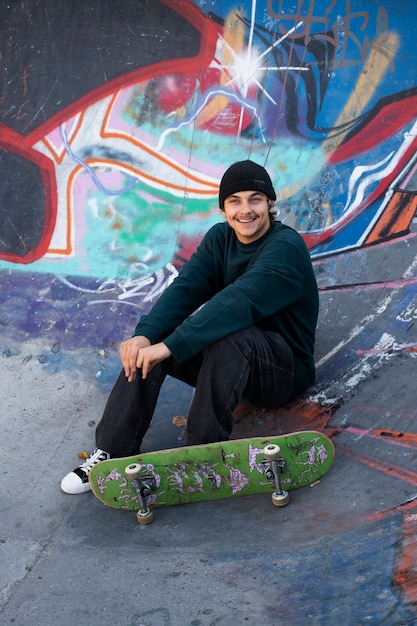 Full shot smiley teen sitting in skatepark