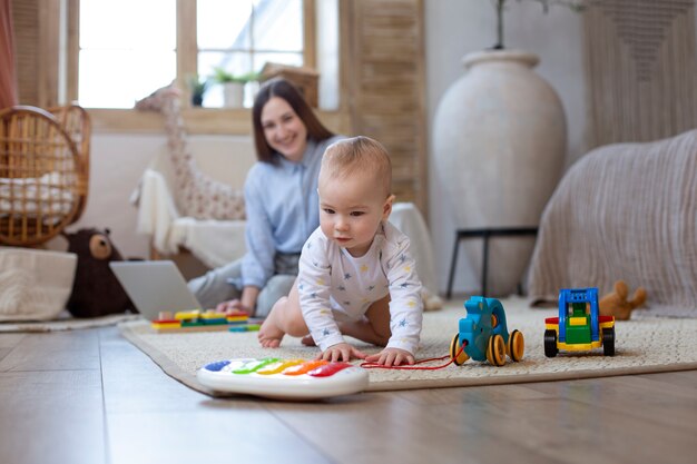 Full shot smiley woman and baby on floor