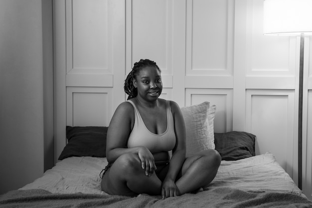 Full shot smiley woman in bed black and white