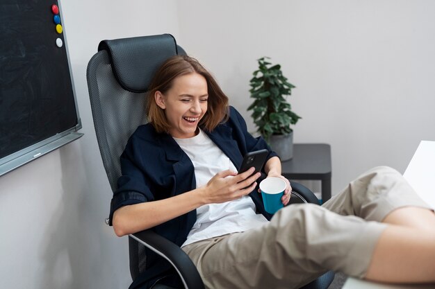 Full shot smiley woman holding phone at work