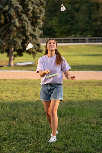 Full shot smiley woman playing badminton