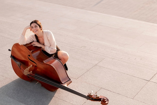 Free photo full shot smiley woman posing with double bass