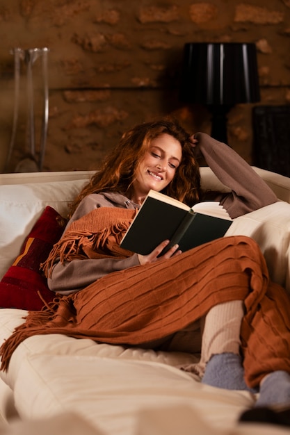 Full shot smiley woman reading on couch