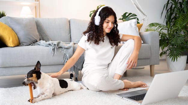 Free photo full shot smiley woman sitting on floor with laptop