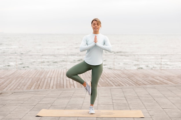 Full shot smiley woman standing on one leg