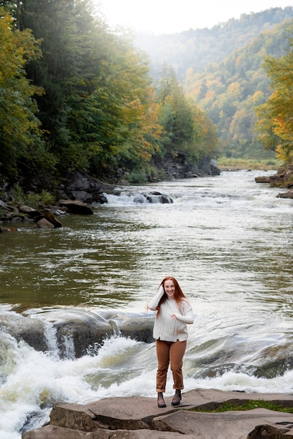 Free photo full shot smiley woman standing on rock