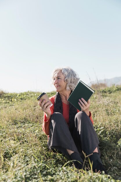 Full shot smiley woman with book outdoors