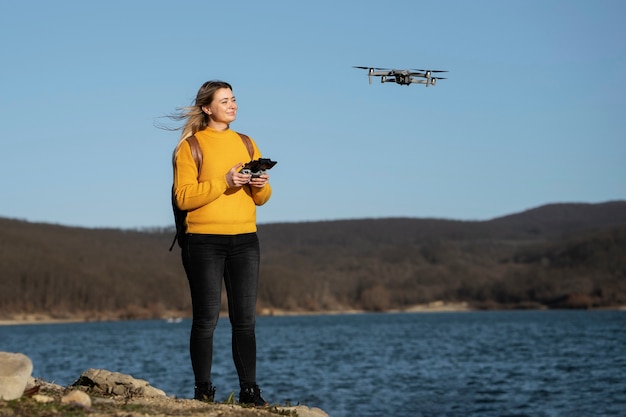 Free photo full shot smiley woman with drone outdoors