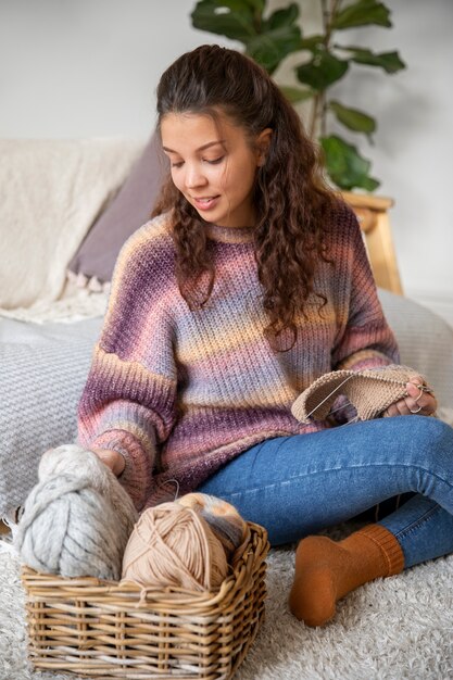 Full shot smiley woman with knitting yarns