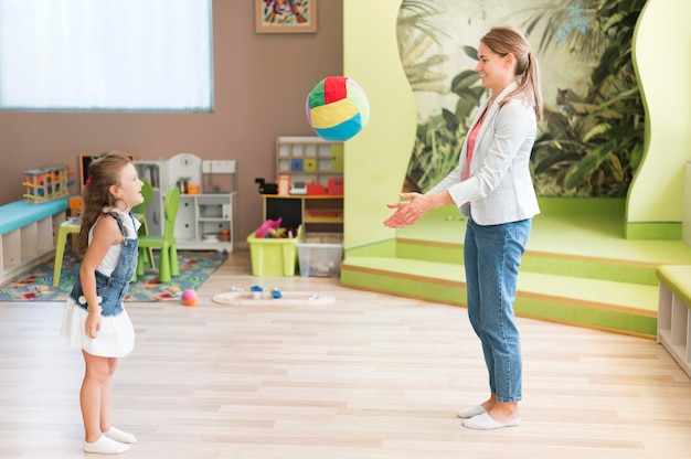 Free Photo full shot teacher and girl playing with ball