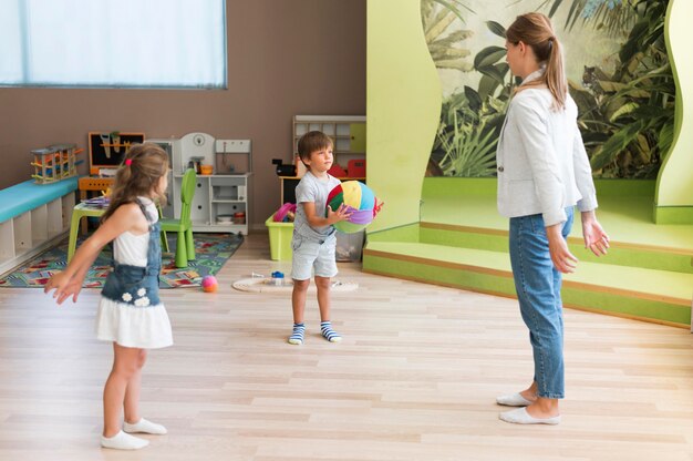 Full shot teacher and kids playing with ball