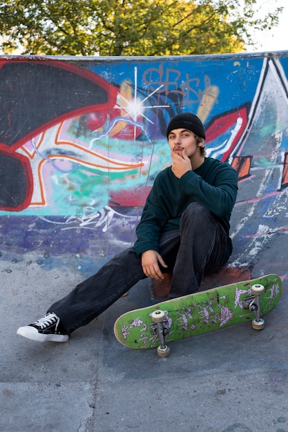 Full shot teen sitting in skatepark