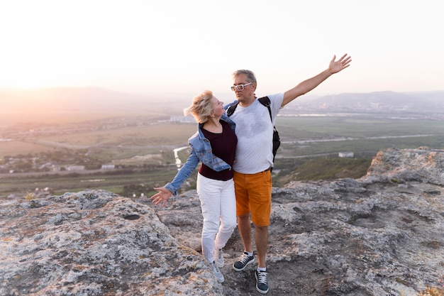 Full shot traveling couple standing on cliff