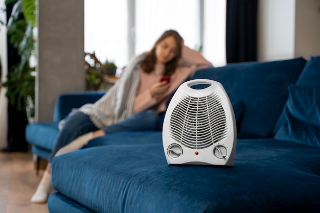 Full shot woman on couch with heater