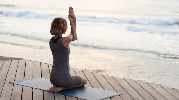 Free photo full shot woman doing yoga pose on mat outside