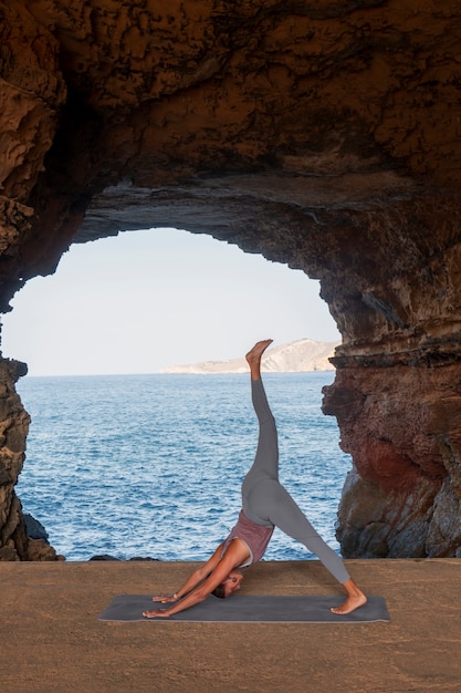 Full shot woman doing yoga pose at seaside