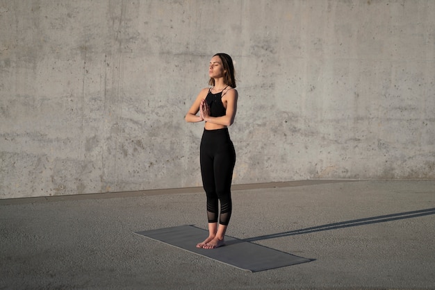 Full shot woman doing yoga with mat