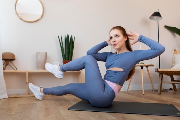 Full shot woman exercising on mat indoors