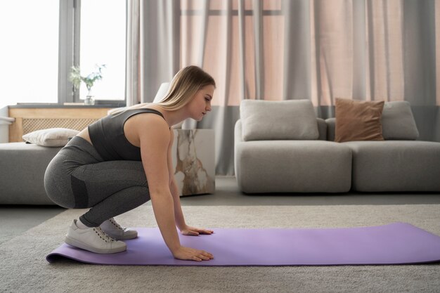 Full shot woman exercising on mat