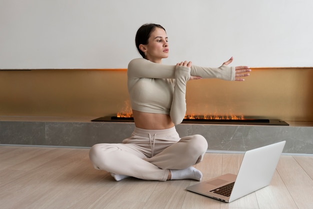 Free Photo full shot woman exercising with laptop inside