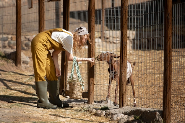 Free Photo full shot woman feeding goat